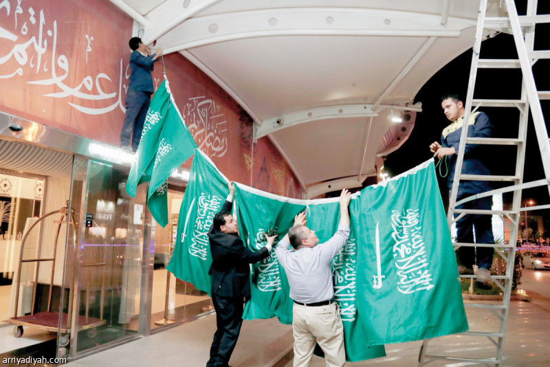 صورة التقطت لعاملين في أحد الكافيهات ينصبون علم السعودية على مدخل إحدى القاعات تصوير: بشير صالح