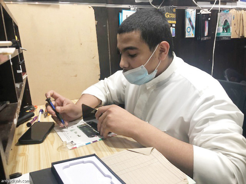 صورة التقطت أمس للزمامي أثناء صيانته هاتفًا ذكيًّا في كشكه في الرياض(صورة خاصة في الرياضية)
