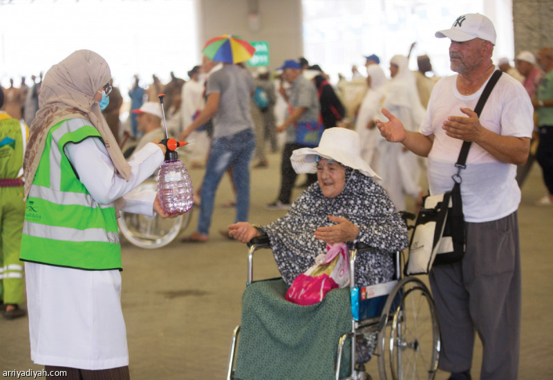 صورة التقطت لإحدى المتطوعات ترش اثنين من الحجاج بالماء قبيل مغادرتهما مشعر منى تصوير: عدنان مهدلي