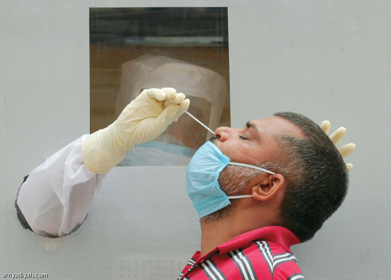 صورة التقطت أمس لعامل صحي يسحب من خلف حاجز عينة أنف من شخص يخضع إلى اختبار الكشف عن فيروس كورونا المستجد في مدينة حيدر أباد الهندية (أسوشيتد برس)